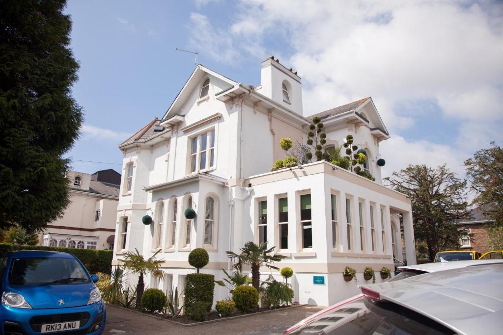 uma casa branca com carros estacionados em frente em Washington House Hotel em Bournemouth