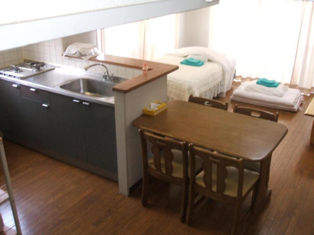 a kitchen with a sink and a table and a bed at Weekly Harbourview Mansion Main Building / Vacation STAY 74567 in Naha