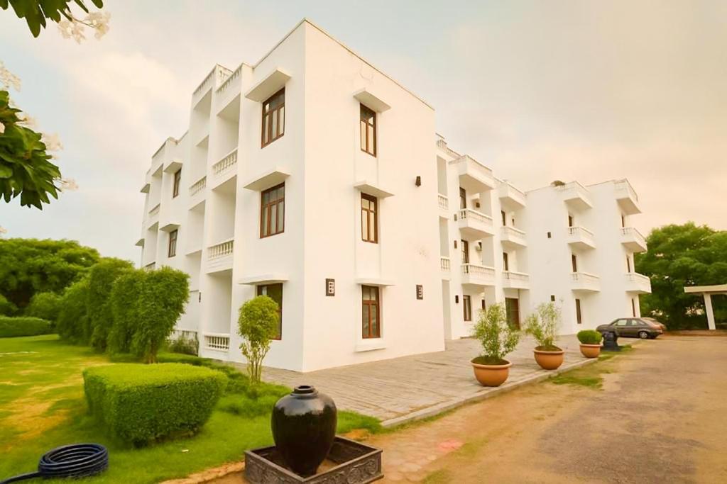 a white building with plants in front of it at Elegance Resort in Vrindāvan
