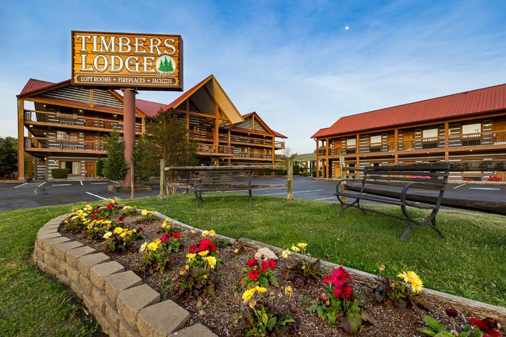 a hotel with a sign and flowers in a garden at Timbers Lodge in Pigeon Forge