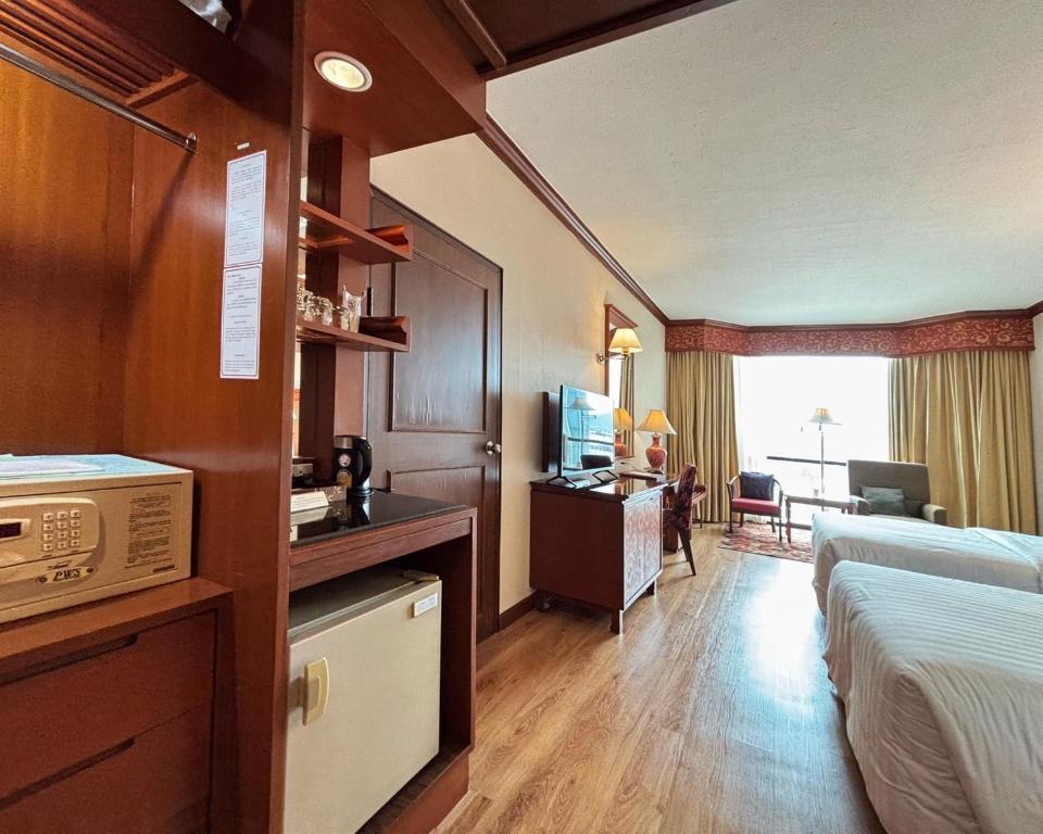 A spacious hotel room with twin beds, a desk, a sitting area and built-in storage.