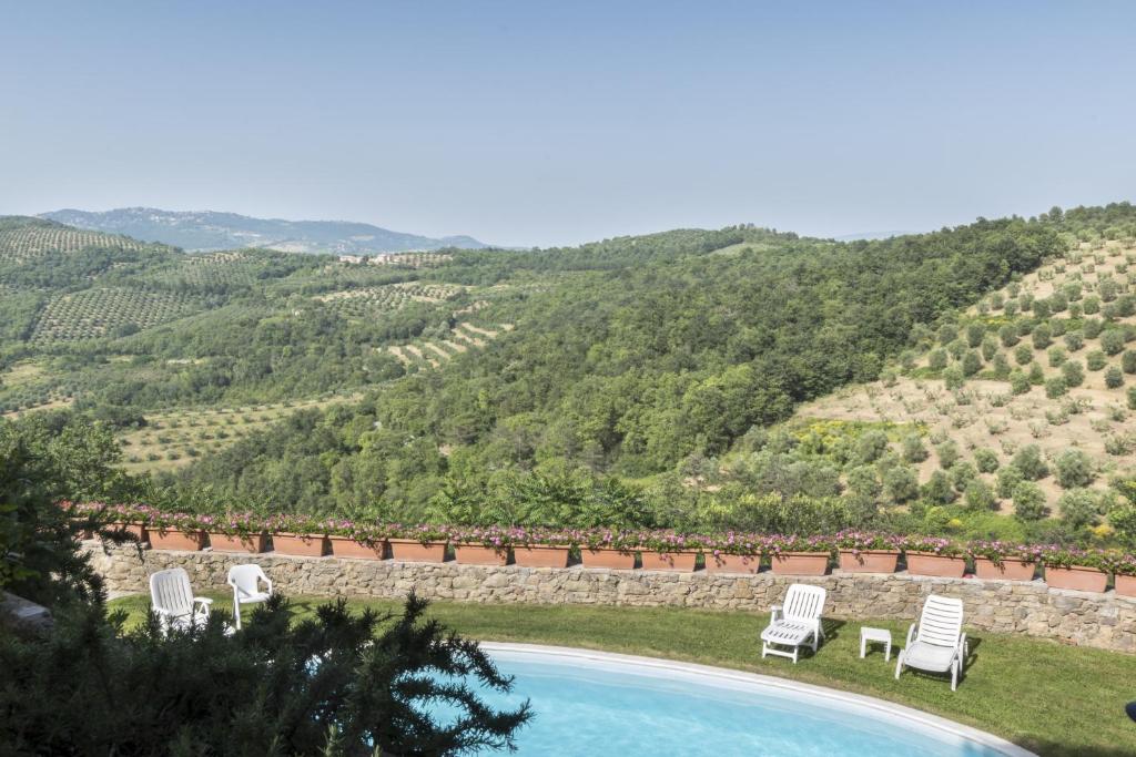 a swimming pool with chairs and a view of a mountain at Agriturismo Borgo Spagnoli in Magione