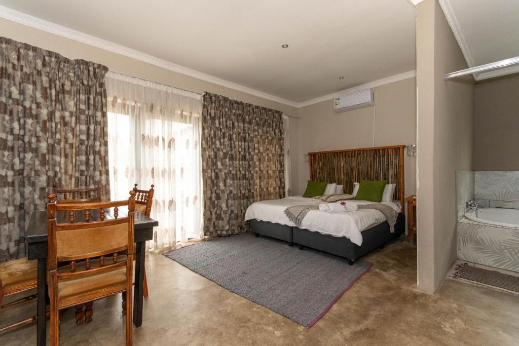 a bedroom with a bed and a desk and a tub at Woodpecker's Guest House in Hazyview