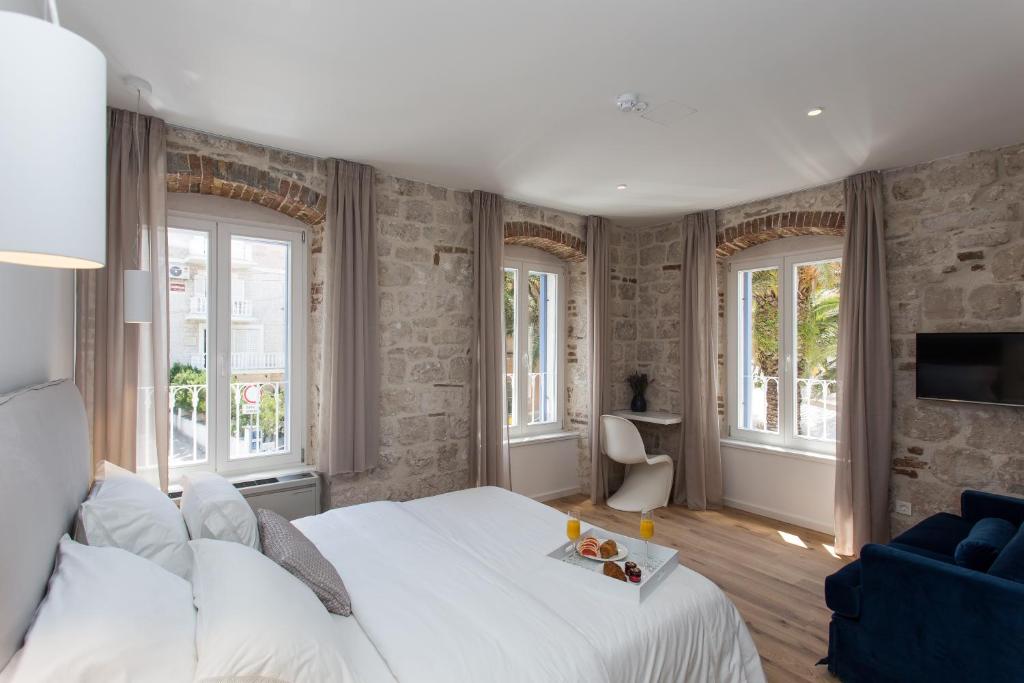 Schlafzimmer mit einem großen weißen Bett und Fenstern in der Unterkunft Bifora Heritage Hotel in Trogir