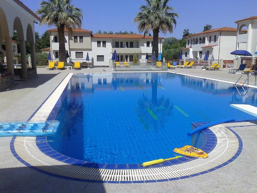 a large swimming pool in a courtyard with palm trees at Amari Hotel in Metamorfosi