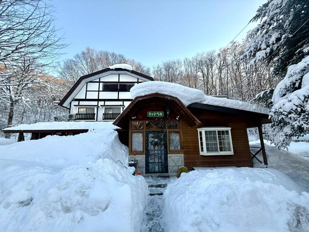 a house covered in snow with two snow banks in front at The Nook Hakuba in Hakuba