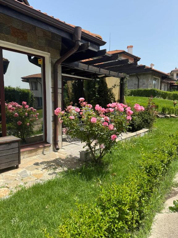 a garden with pink roses in front of a house at Villa Rada, Bay View Villas in Kosharitsa