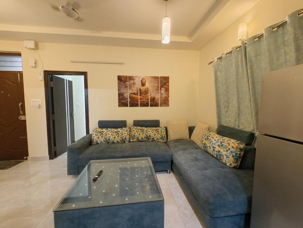a living room with a blue couch and a refrigerator at M's Cozy Unwind - Hazel in Bengaluru