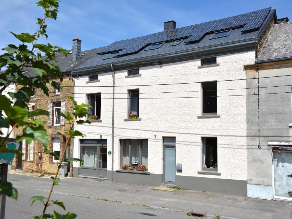 a white brick building with a solar roof at Holiday Home - Entre Gaume et Ardenne in Florenville