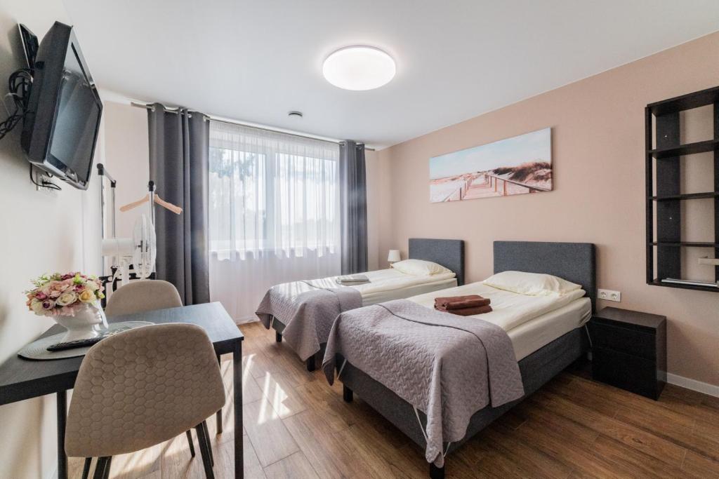 a hotel room with two beds and a desk and a tv at Svečių namai Imperija in Šiauliai