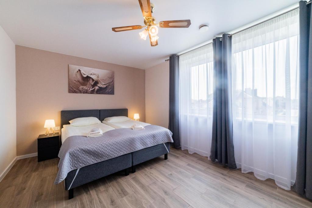 a bedroom with a bed and a ceiling fan at Svečių namai Imperija in Šiauliai