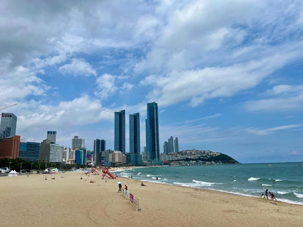 a beach with people and the ocean and buildings at Haeundae HaeRium Hotel in Busan