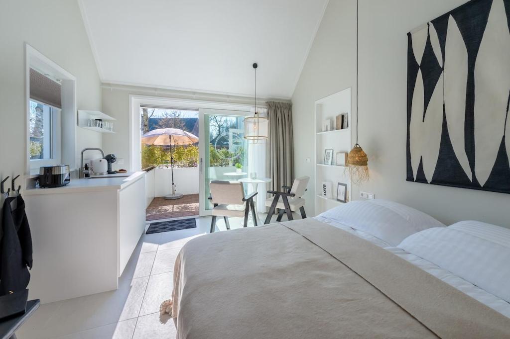 een witte slaapkamer met een groot bed en een keuken bij Slow living Suite 1 Oostkapelle in Oostkapelle