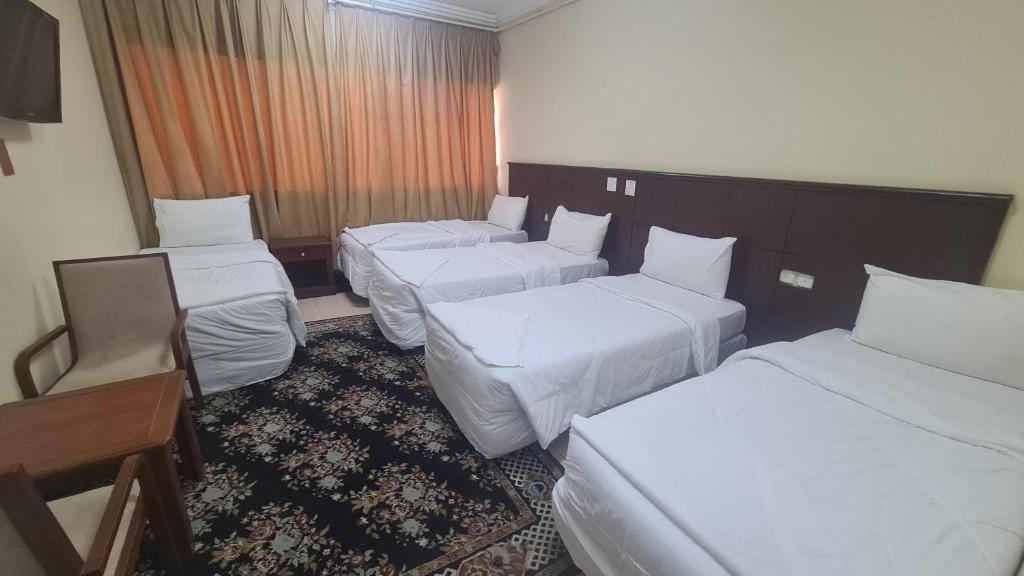 a hotel room with three beds and a table and chairs at فندق جوهرة الشروق in Az Zahrāʼ