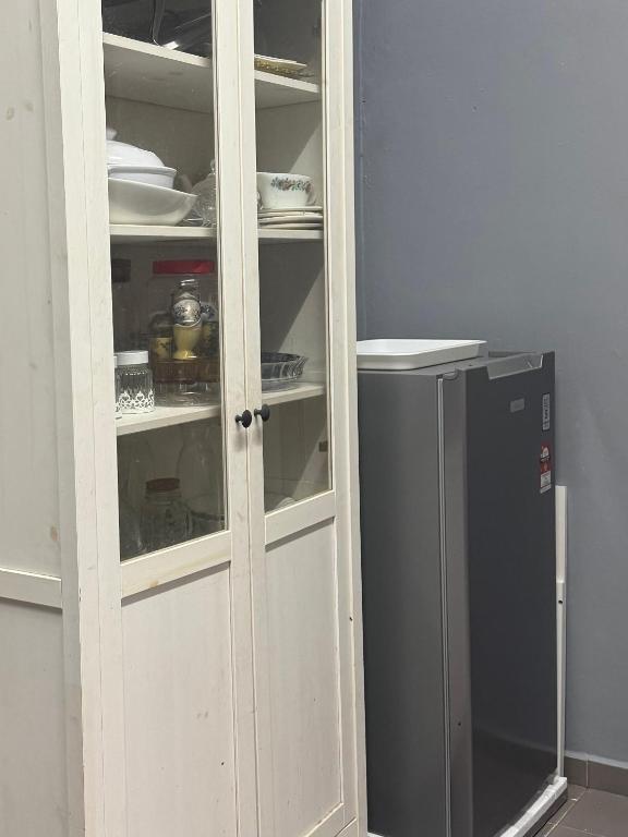 a white cabinet next to a refrigerator in a room at Homestay Mr in Temerloh