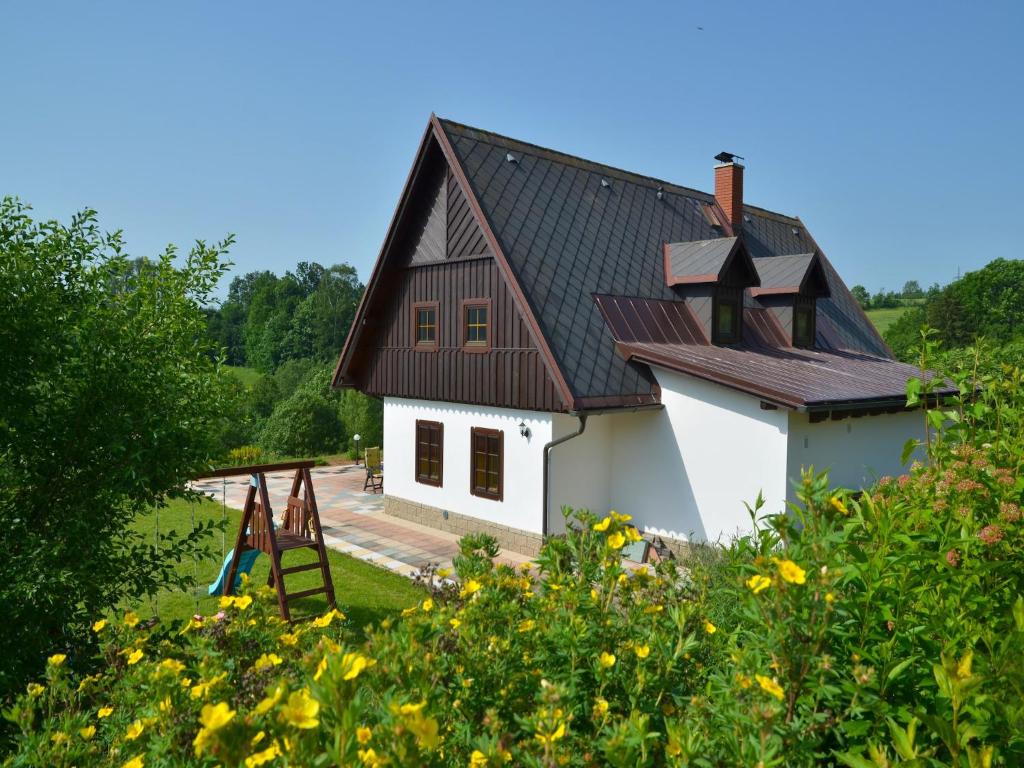 a white house with a black roof and a yard at Stupná Holiday Home with Garden in Vidochov