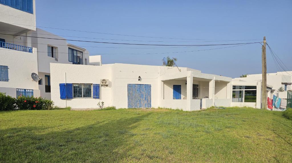 una casa blanca con una puerta azul en un patio en Nassime 1, en Cabo Negro