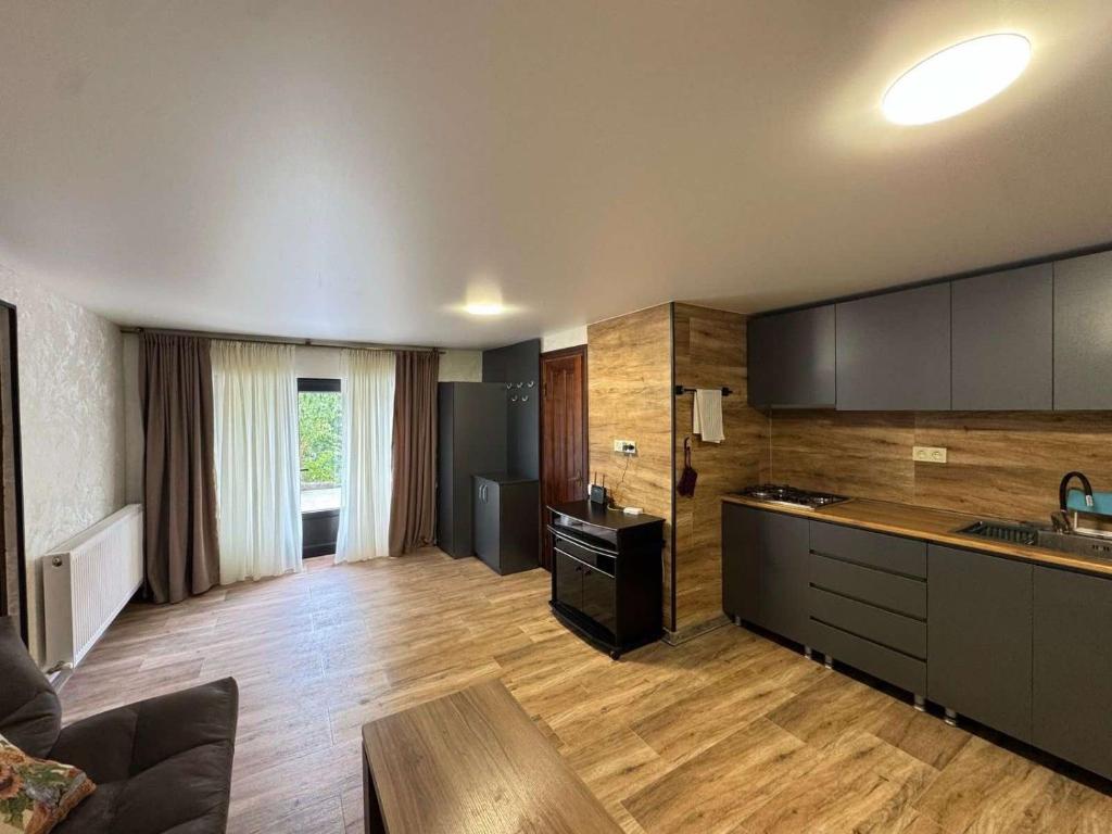 a large kitchen with wooden flooring and a living room at House Lia Apartment Likani in Borjomi