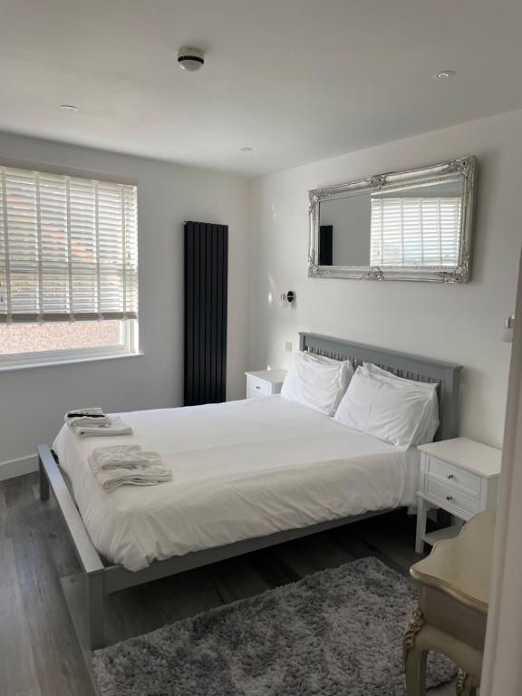a white bedroom with a bed and two windows at Bay view apartment in Penzance