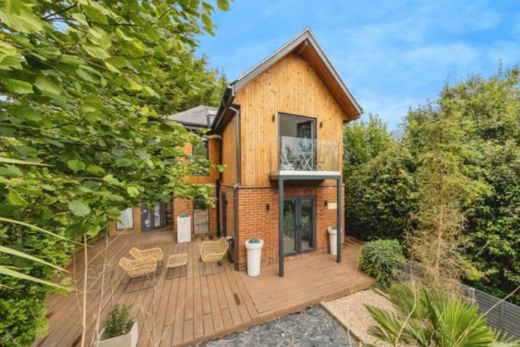 a home with a wooden deck and trees at Modern Retreat in Kent Countryside in Tonbridge
