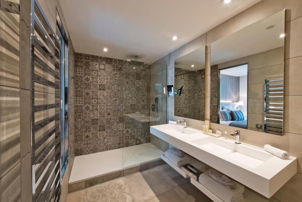 a bathroom with two sinks and a mirror at Golden Tulip Sophia Antipolis - Hotel &amp; Spa in Valbonne