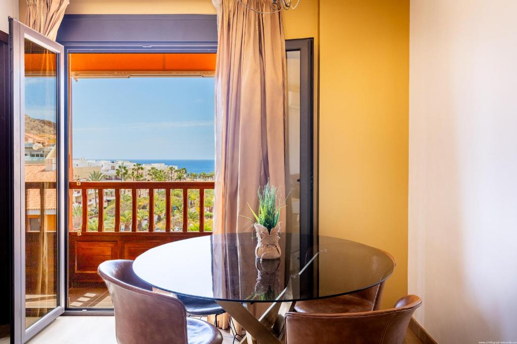 a dining room with a table and chairs and a balcony at Sunset Palm Mar - Family Friendly Suites in Palm-Mar