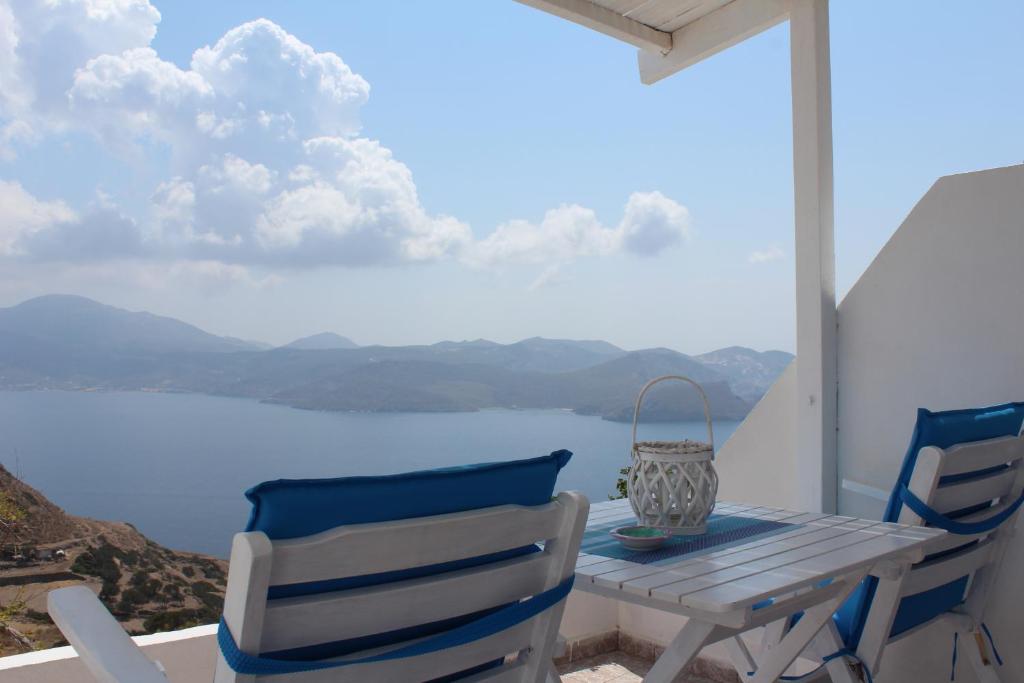 a table and chairs on a balcony with a view of the water at Studios Betty in Plaka Milou