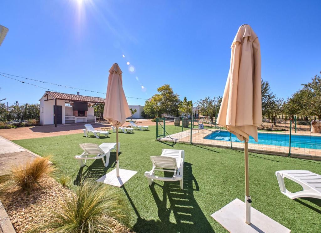 a group of umbrellas and chairs next to a pool at Casa Rural Entre Almendros in El Toboso
