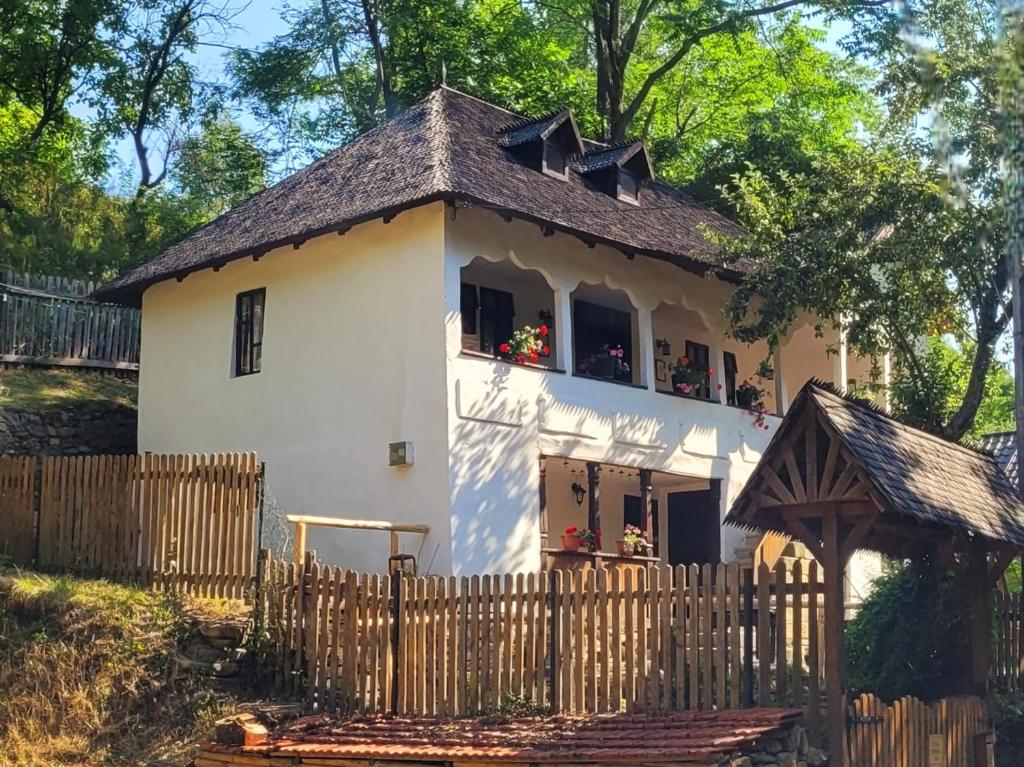 a small white house with a wooden fence at Conacul Copilăriei in Ruginoasa