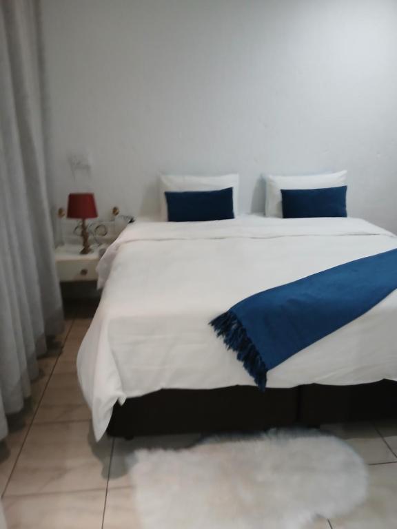 Un dormitorio con una gran cama blanca con almohadas azules. en Russell's Rest Apartments, en Johannesburgo