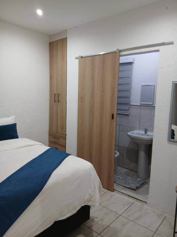 a bedroom with a bed and a bathroom with a sink at Russell's Rest Apartments in Johannesburg