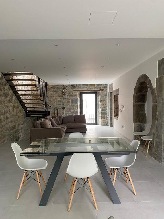 a living room with a glass table and white chairs at Quiet village house in L’ Esquirol