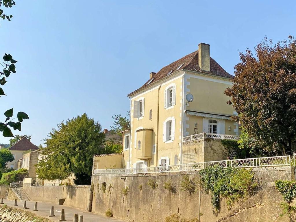 a yellow house on top of a stone wall at Charmante maison XIXe siècle bord de Vézère - FR-1-824-6 in Le Bugue