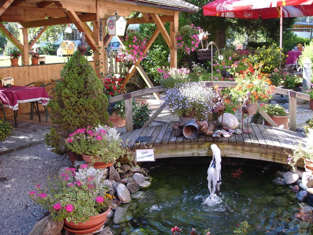 a pond with a fountain in a garden with flowers at Wanderhotel Grüner Baum in Bach