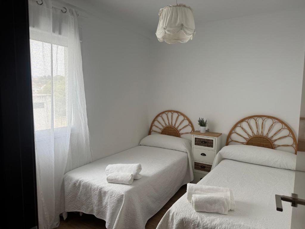 een kamer met 3 bedden met witte lakens en een raam bij Alojamiento Carioca in Almodóvar del Río