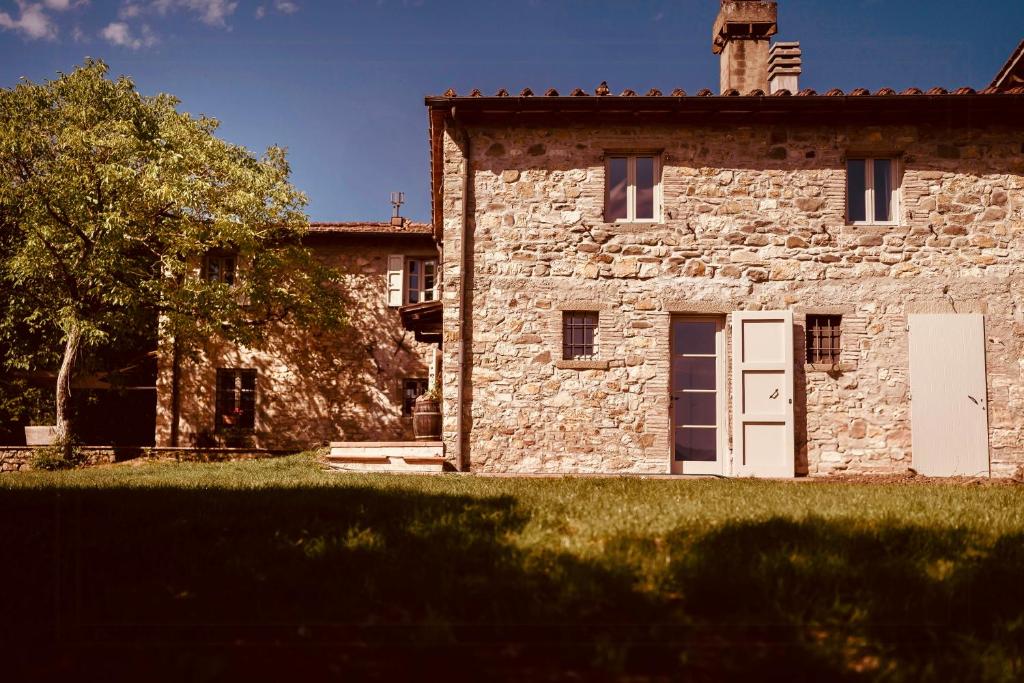 an old stone building with a white door and a tree at Restored Farmhouse In Tuscan Casentino Hills in Poppi