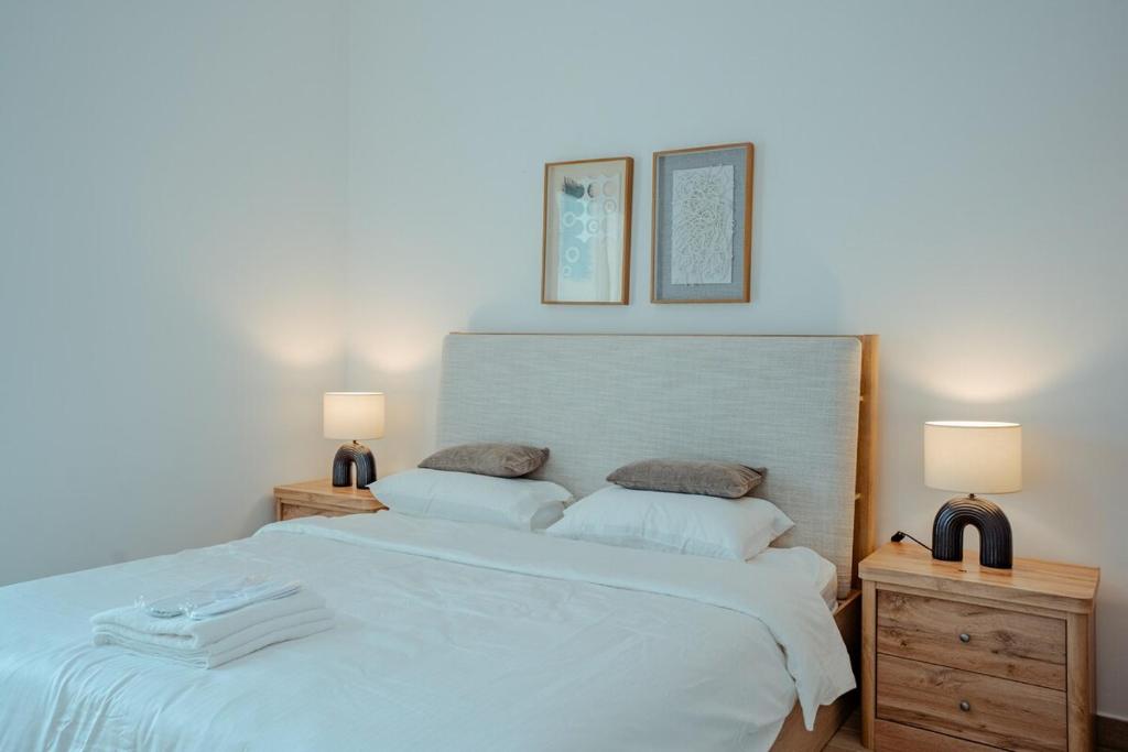Un dormitorio con una gran cama blanca con dos lámparas. en Modern 1BR with Lake View Yas Island Stay for 4, en Abu Dabi
