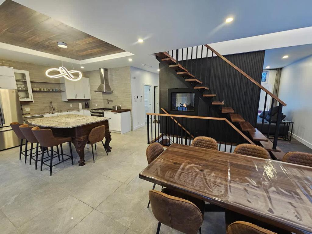 a kitchen and living room with a staircase and a table at Le repaire du hibou - Piano & Spa in Petite-Rivière-Saint-François