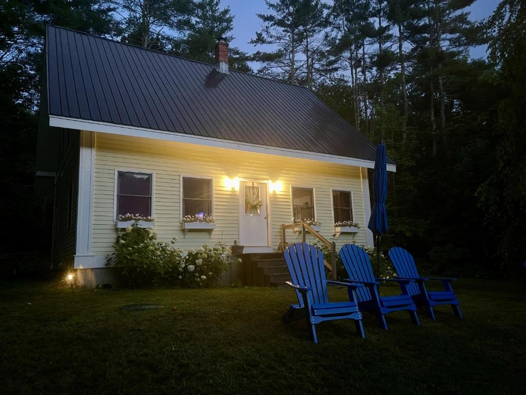 a white house with two blue chairs in front of it at Turner Hill Cottage in West Townshend