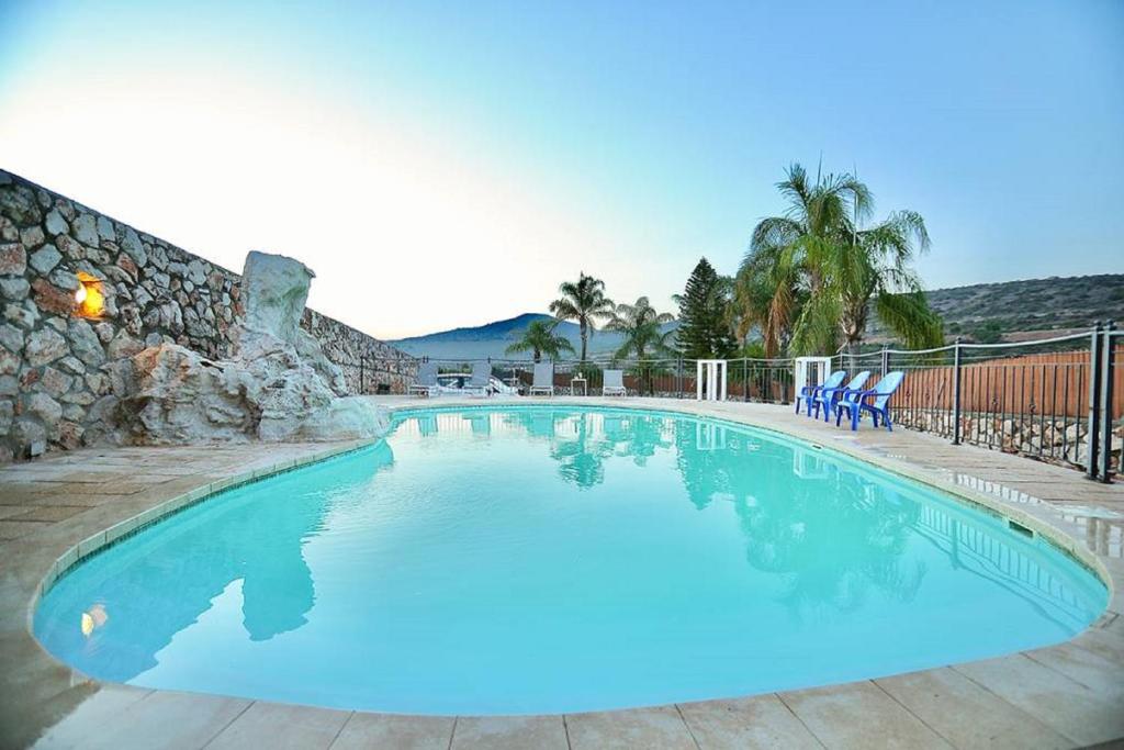 a large blue swimming pool with a stone wall at אצולת הגליל in Kallanit