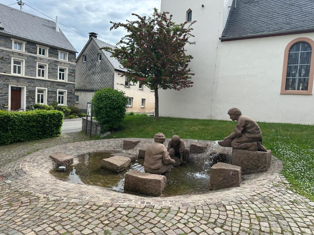 a statue of people sitting in a fountain in a yard at Ferienwohnungen zum Goldgräber in Bernkastel-Kues