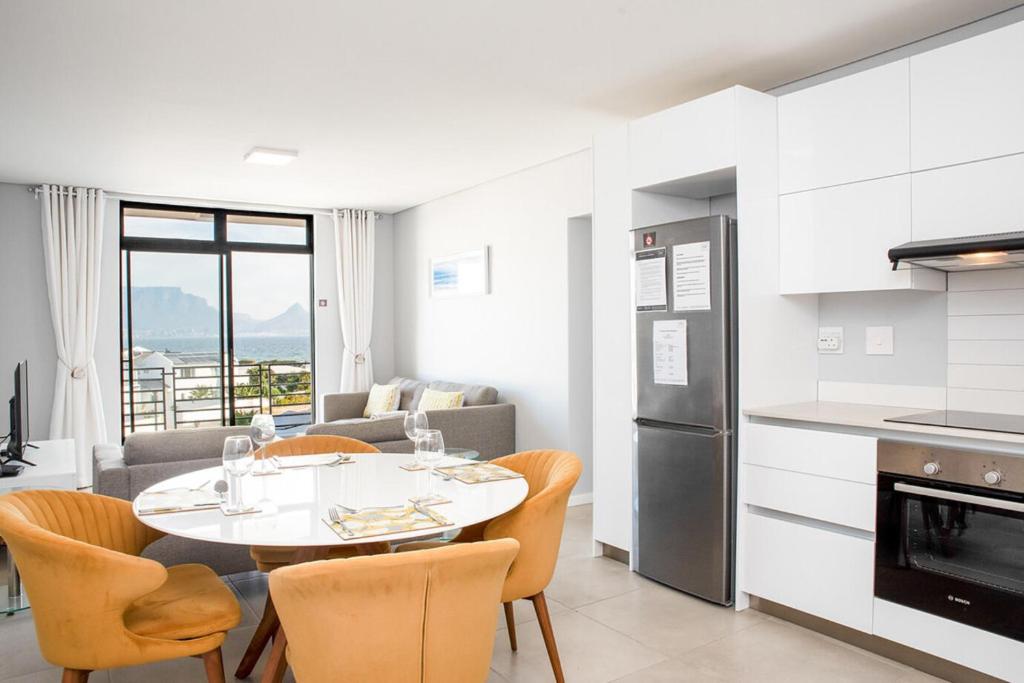 a kitchen and living room with a table and chairs at Beachfront 2 bed w swimming pool, Blouberg 54 Beach Break in Bloubergstrand