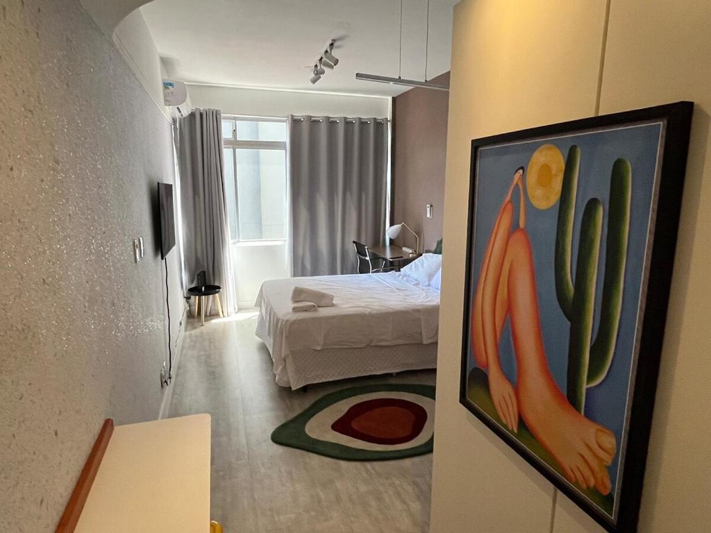 a room with a bed and a painting on the wall at Studio XV Centro Florianópolis Centro Sul Eventos in Florianópolis