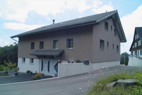 a large house with a roof on a street at Ferienwohnung, Ferienhof Wald in Goldingen
