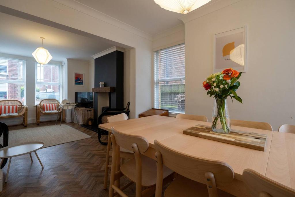 een woonkamer met een eettafel met een vaas met bloemen bij Gorleston Beach House by Leap Escapes in Gorleston-on-Sea