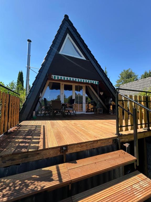 a house with a large wooden deck with a porch at Ferienhaus im Feriendorf Freilingen (Eifel). in Freilingen