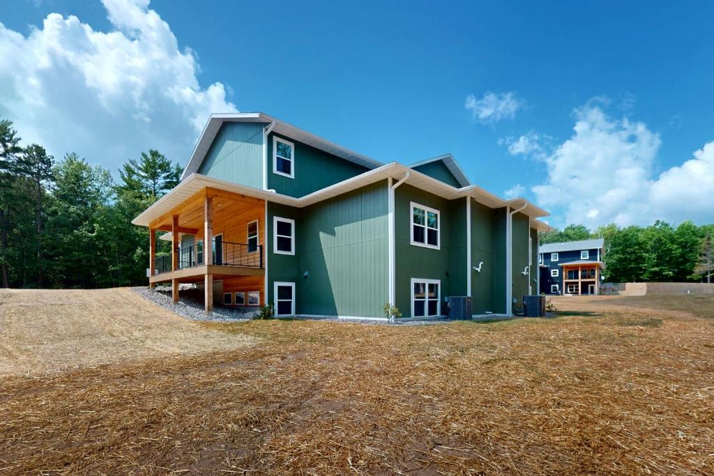 a house with a green exterior on a field at The Crossing at Lake Forest- 35 in Eagle River