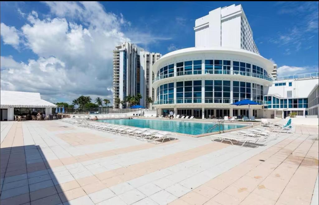 un gran edificio con piscina y tumbonas en UNIT #1108 Castle Beach Club Condominium, en Miami Beach