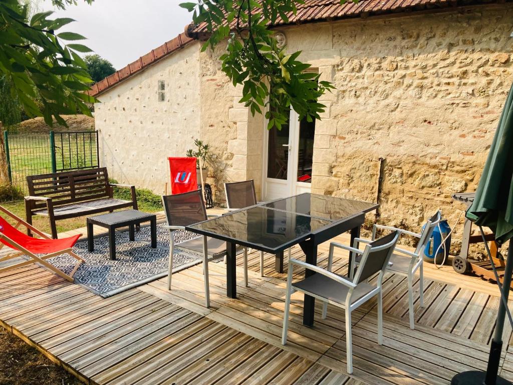 a glass table and chairs on a wooden deck at Petite maison à la campagne in Saint-Germain