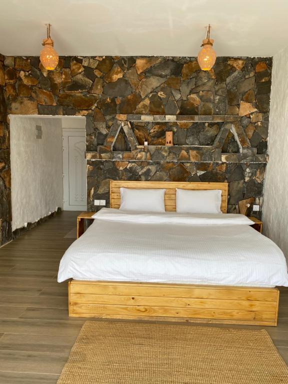 a bedroom with a large bed with a stone wall at Panorama Guest House Jabal Shams in Sa‘ab Banī Khamīs